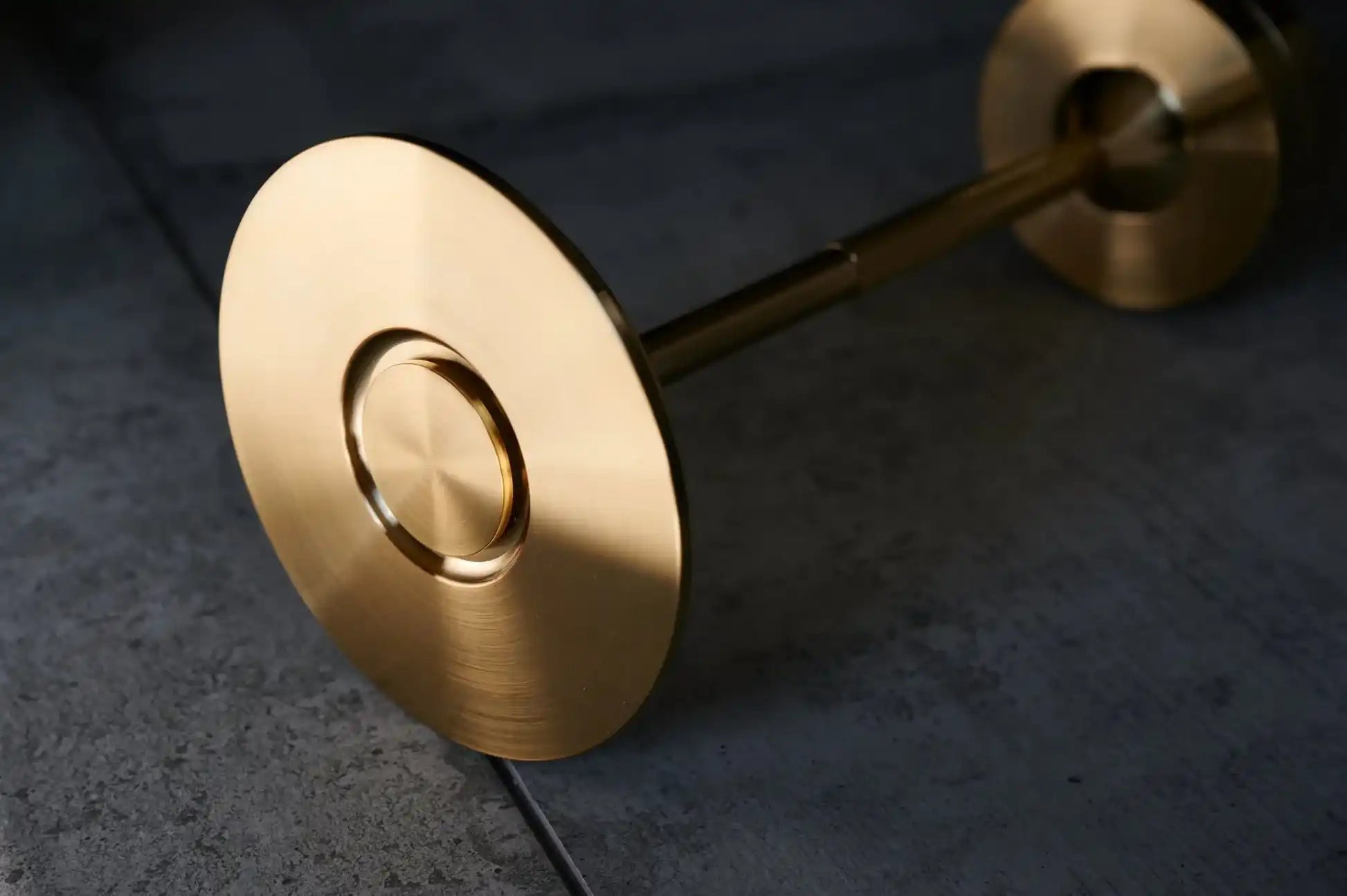 A sleek, golden barbell with polished, circular weight plates.