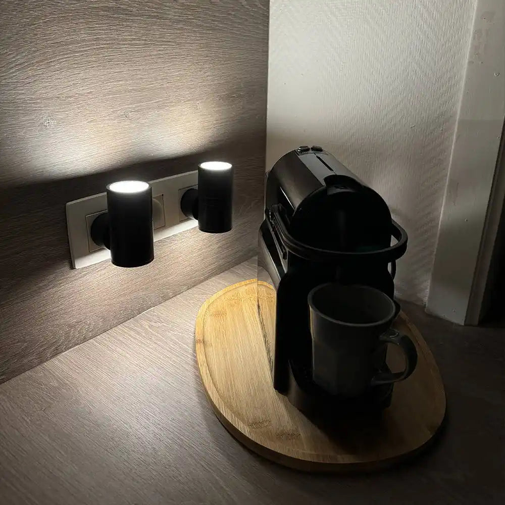 A black coffee machine with a mug on a wooden tray.