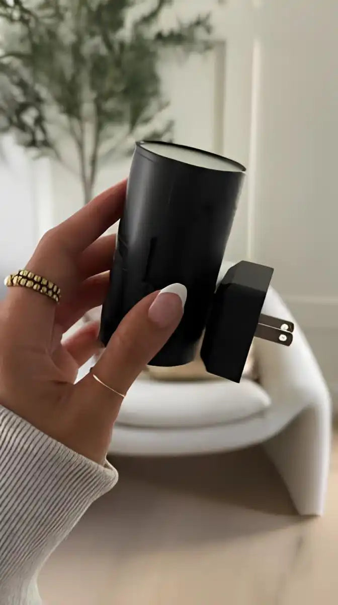 A black cylindrical air freshener with a two-pronged electrical plug.