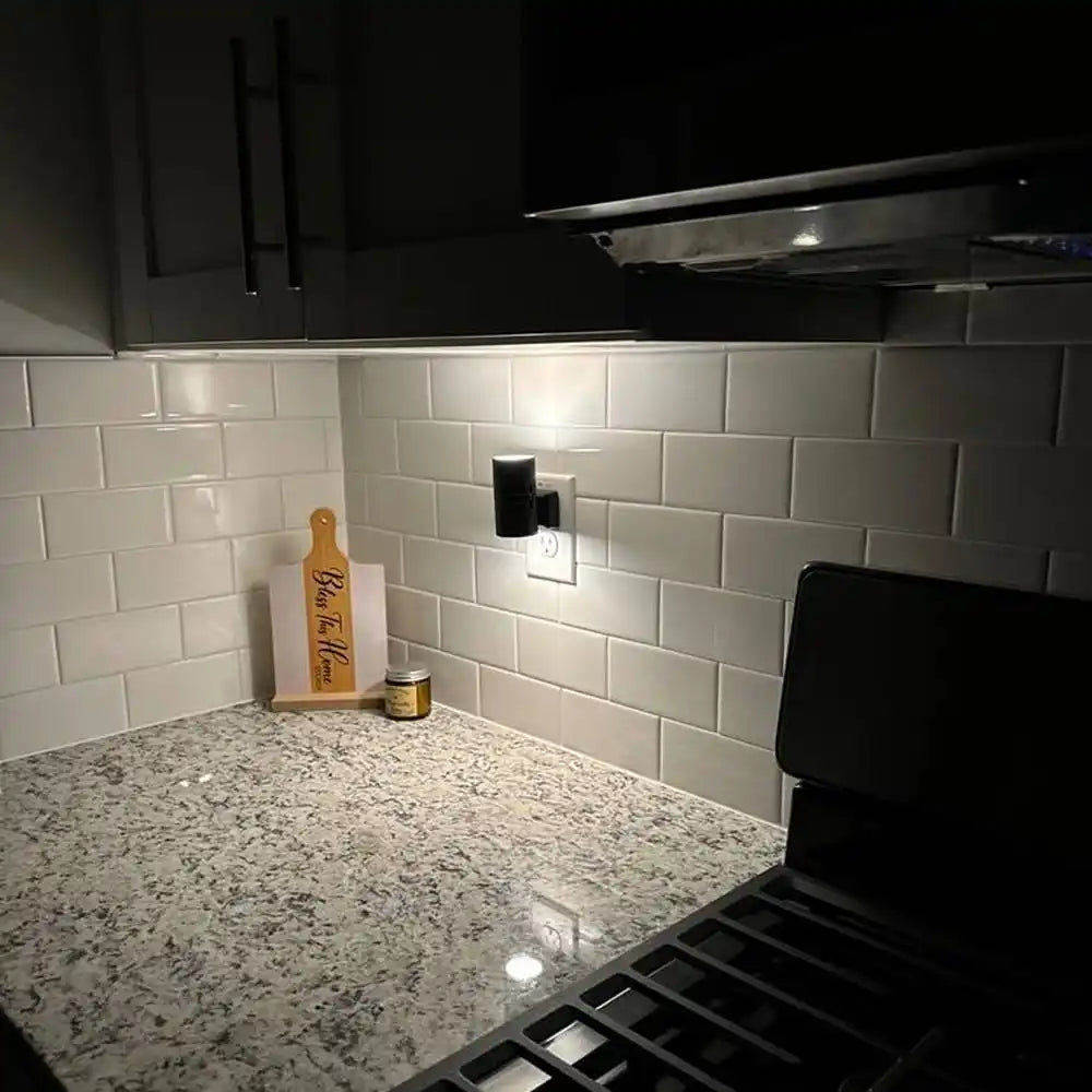 A black cylindrical night light plugged into a wall outlet.