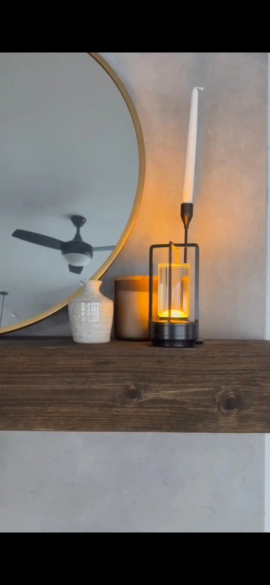 A black metal candle holder with a clear glass cylinder and a white taper candle.