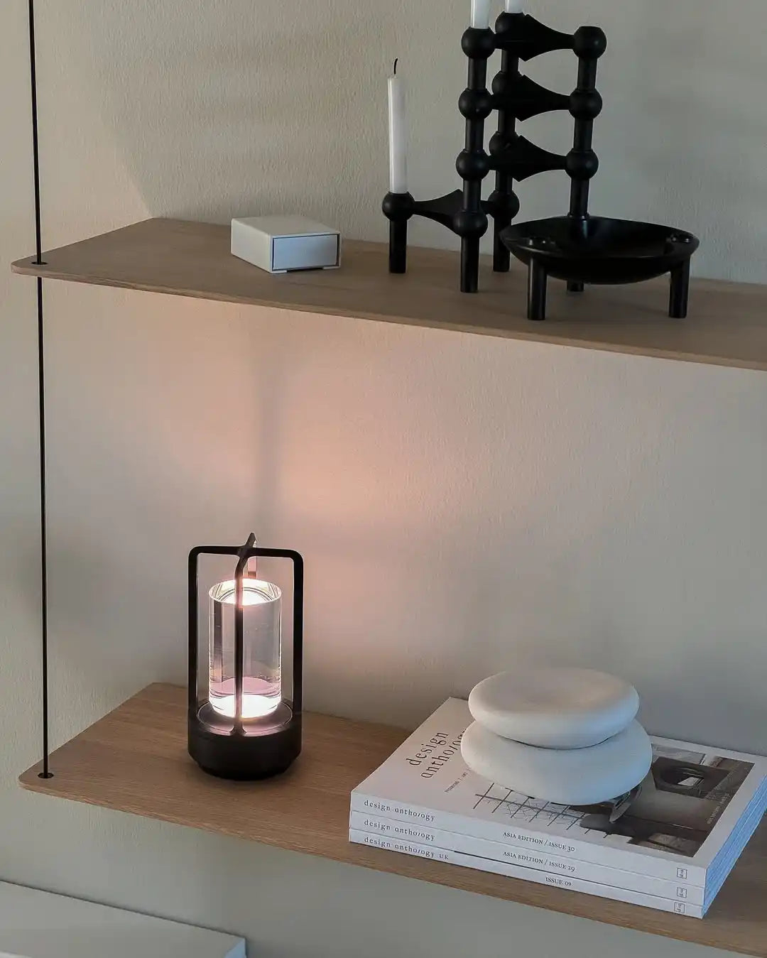 A black modular candle holder with white candles and a black bowl-shaped candle holder with three legs.