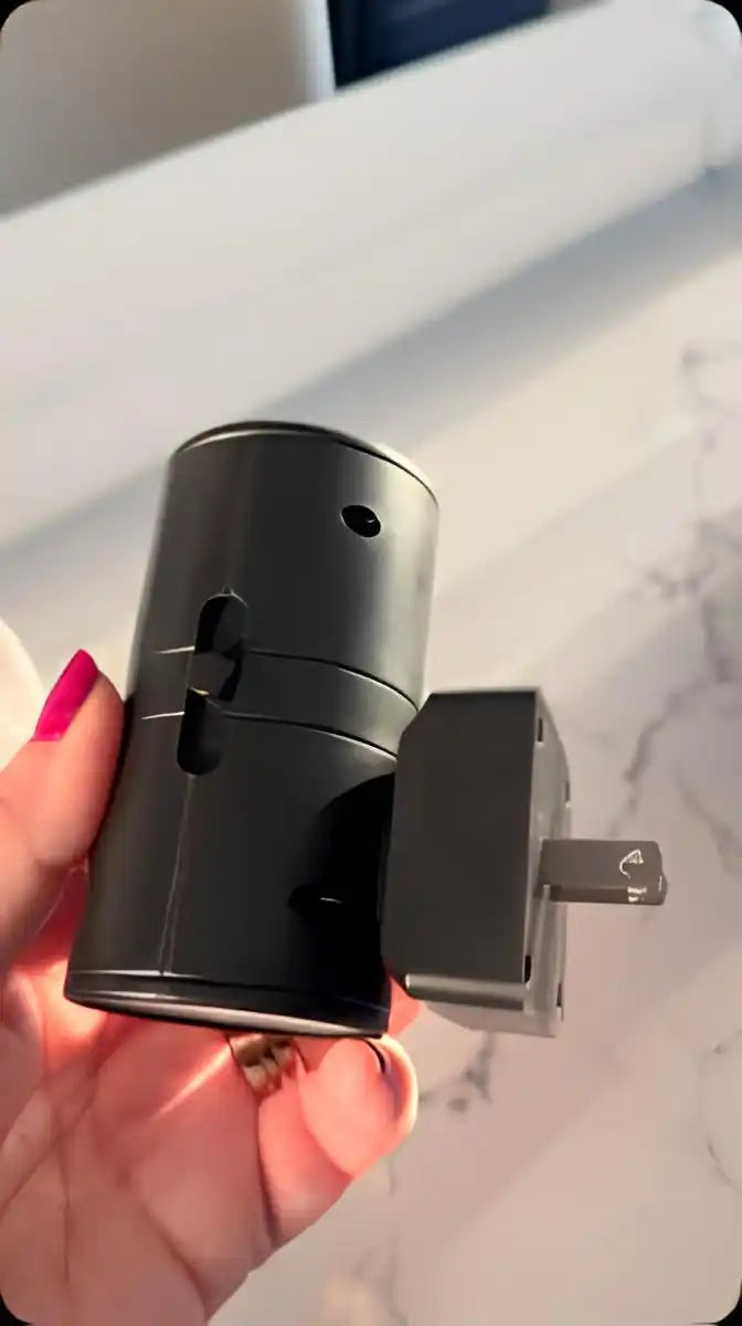 A black universal travel adapter with retractable prongs.