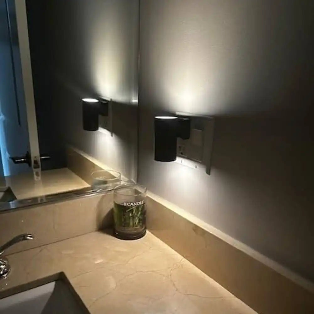 A black wall-mounted cylindrical light fixture casting light upwards and downwards.
