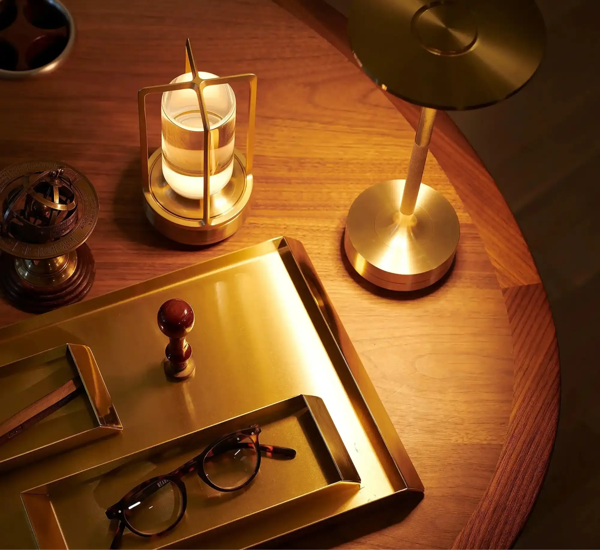 A collection of brass desktop accessories, including a tray, glasses, lamp, and other decorative items.