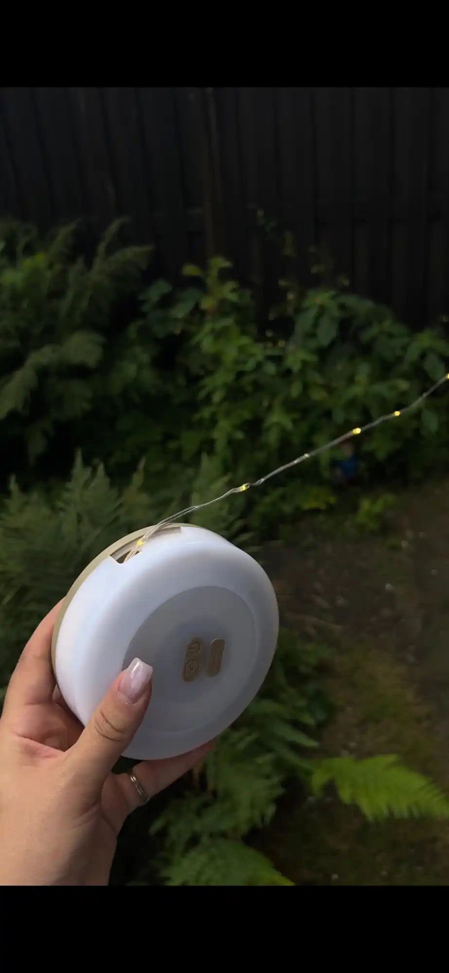 A hand holding a spool of small, delicate string lights.