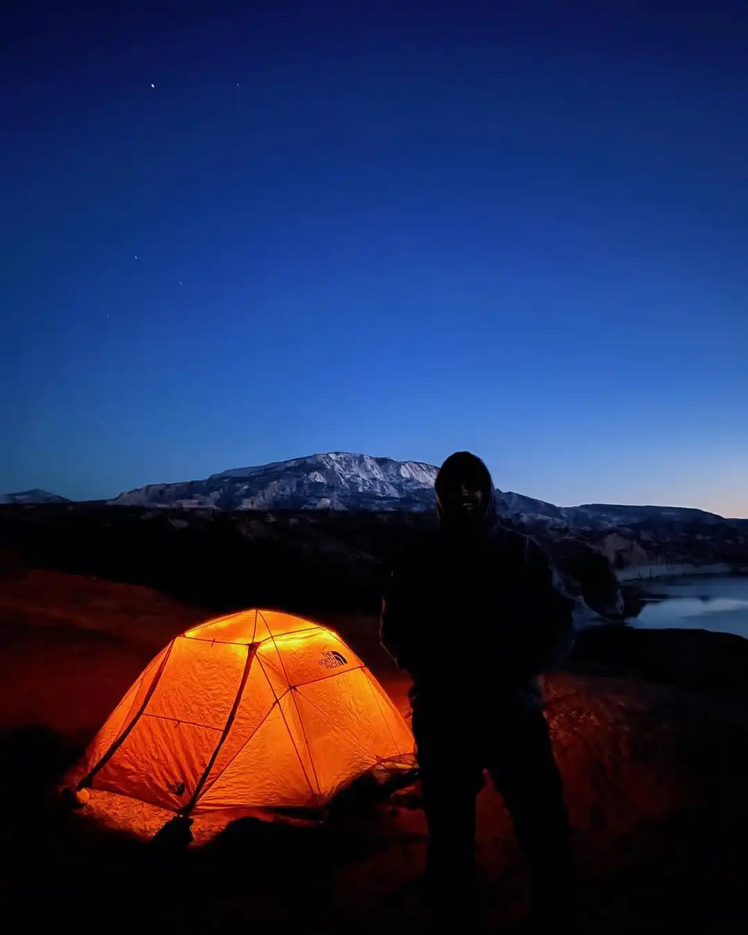 An illuminated orange camping tent.