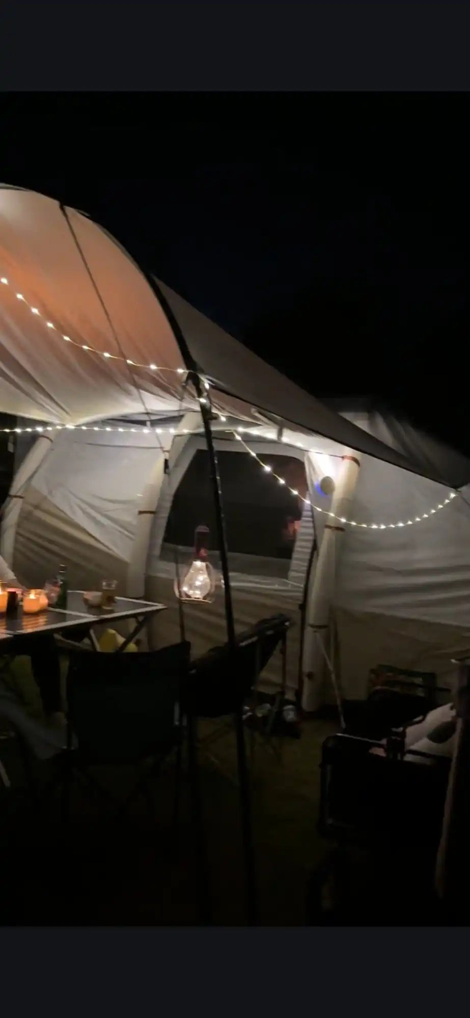 Illuminated tent with a patio setup.