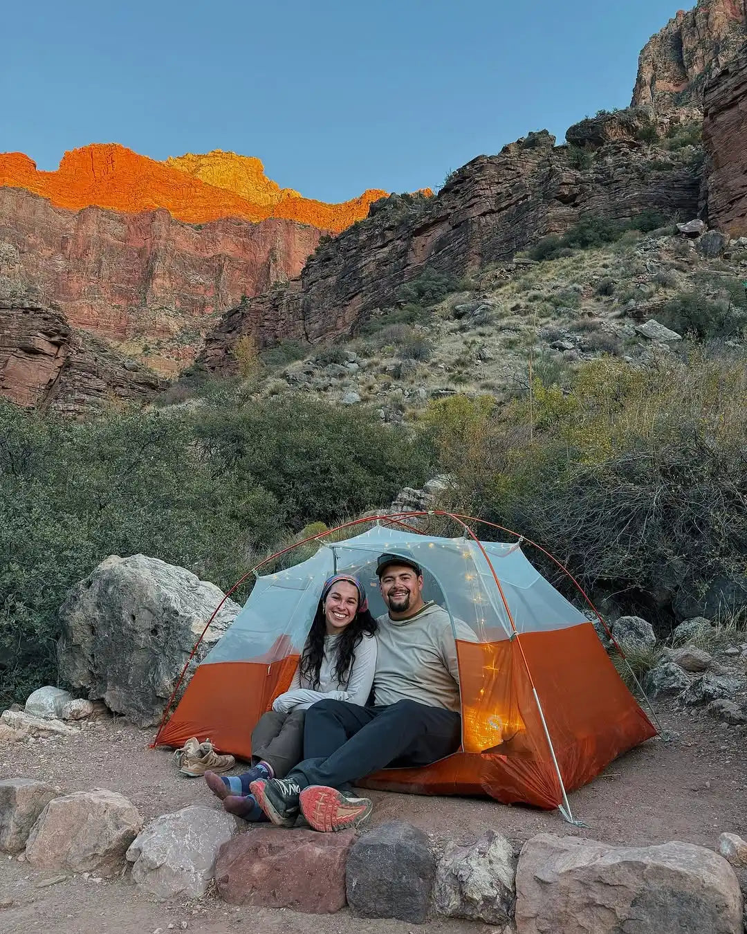 A two-person camping tent with an orange and light-colored fabric.