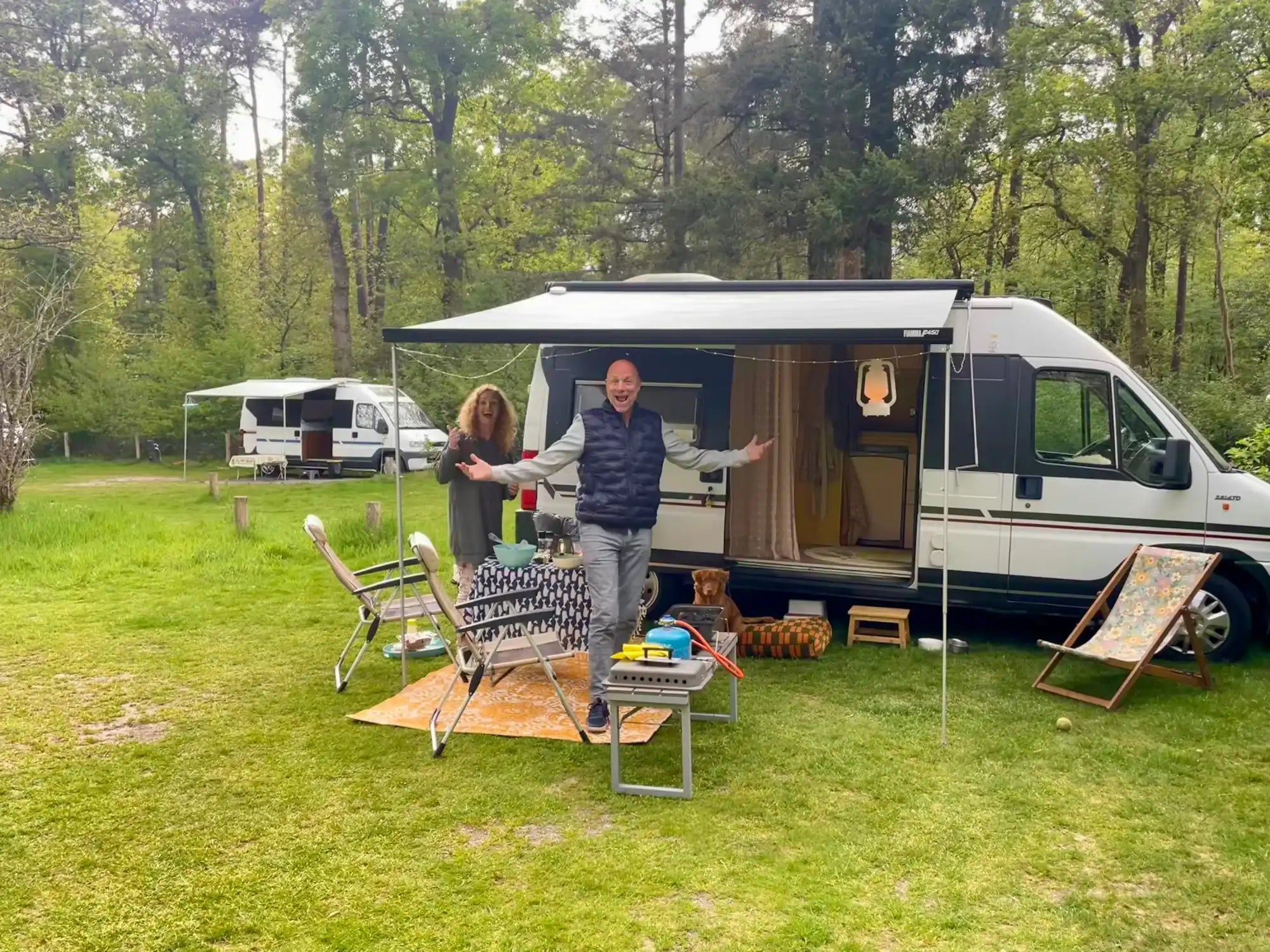 A white recreational vehicle with an extended awning and an open side door revealing a cozy interior.