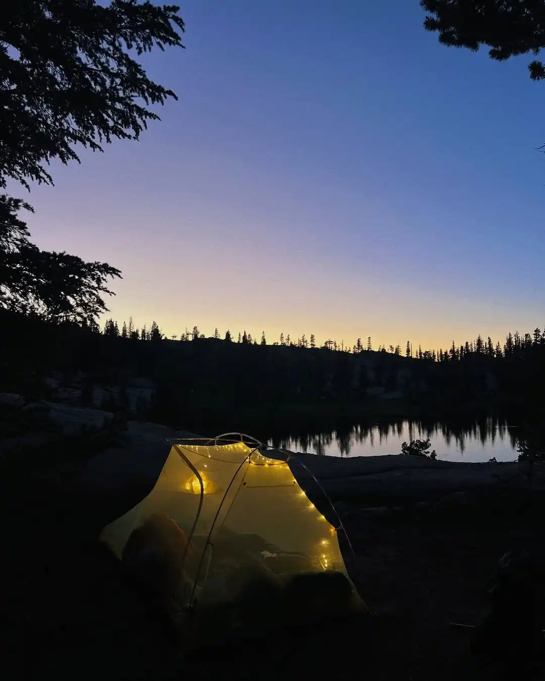 A yellow illuminated camping tent with string lights.